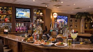Eine Bar mit Fernseher, der ein Sportevent zeigt, verschiedenen Helmen und einer Auswahl an Getränken und Snacks auf der Theke.