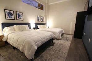 Quarto com duas camas, parede de tijolos e obras de arte na parede.