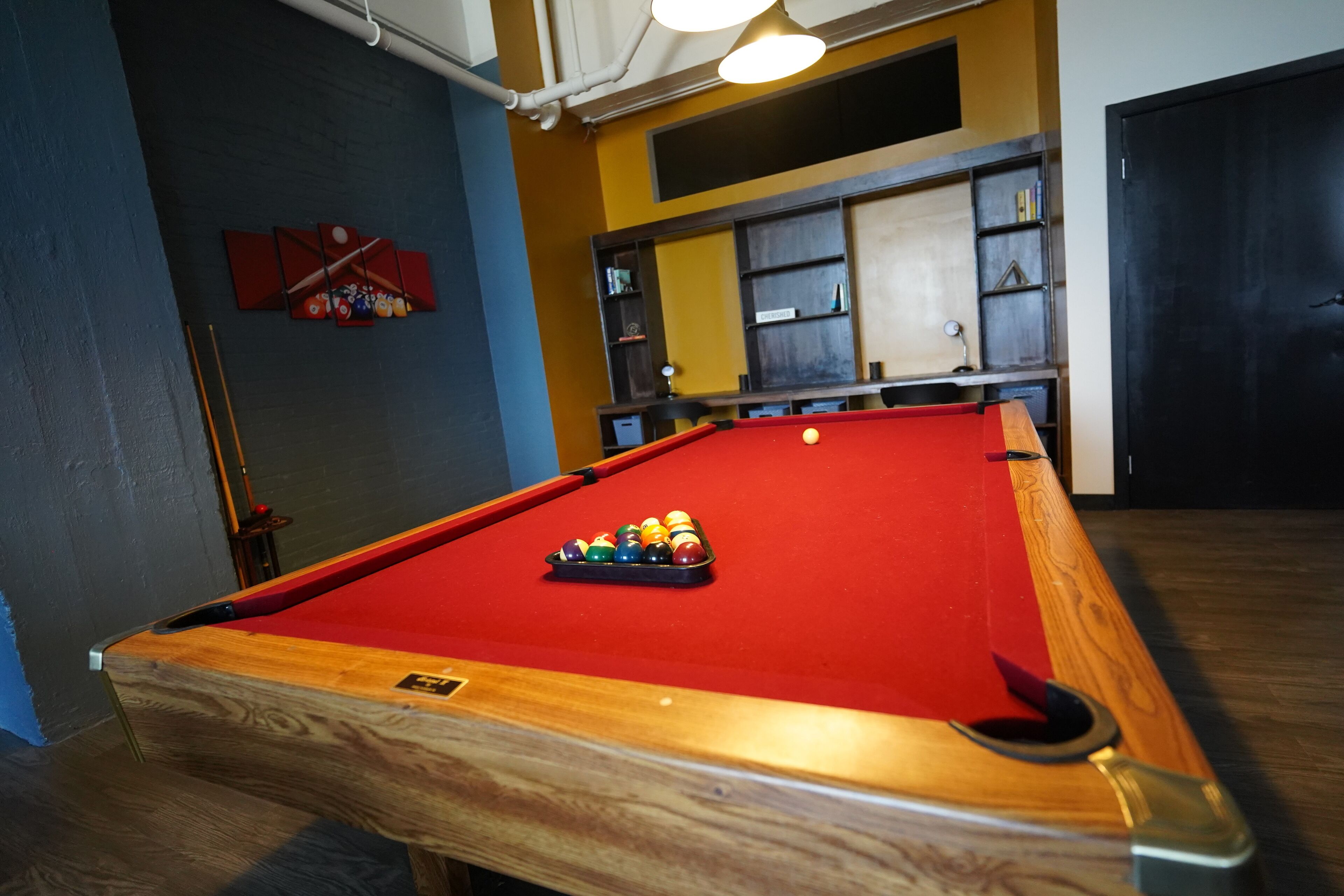 A pool table with a red felt surface and a set of billiard balls.