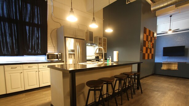 A modern kitchen with a central island, bar stools, and a flat-screen TV mounted on the wall. - 424 Gold Way- 3Bed/2Bath Apartment (Pittsburgh)
