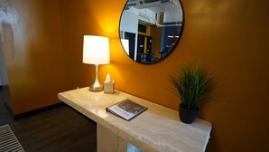 A reception desk with a lamp, a welcome brochure, a potted plant, and a mirror reflecting the interior. - 424 Gold Way- 3Bed/2Bath Apartment (Pittsburgh)