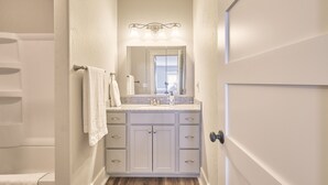 Une salle de bain avec un meuble-lavabo blanc, un miroir et une douche.