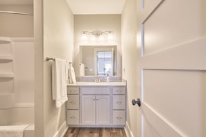 A bathroom with a white vanity, a mirror, and a shower.