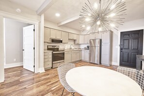A modern kitchen with wooden flooring, stainless steel appliances, and a unique ceiling light fixture.