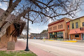 A street view with a row of buildings, including a local art crafts store and a restaurant with outdoor seating.