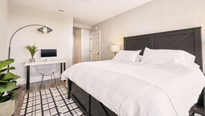 Une chambre d’hôtel avec un lit, un bureau, une chaise et une plante en pot.