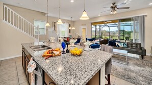A spacious kitchen with granite countertops, a central island, and a dining area with a sofa and coffee table. - Private Conservation View With Theme Rooms and Beautiful Pool Area, Perfect for Families #5st4591 (Davenport)