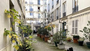 A narrow courtyard with potted plants and a dog. - 1 Bedroom Apartment in Paris (Paris)
