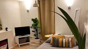 A modern bedroom with a bed, bedside table, TV, and a potted plant. - 1 Bedroom Apartment in Paris (Paris)