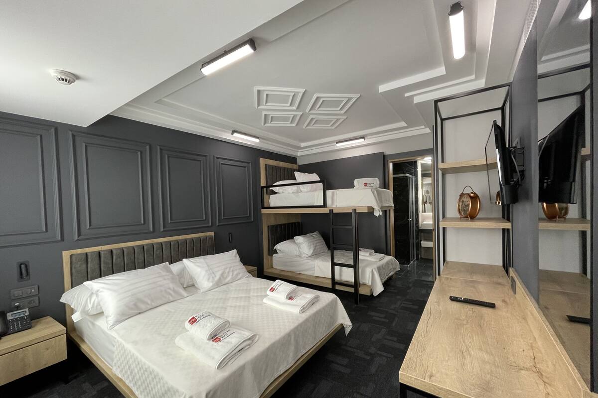 A hotel room with a large bed, a smaller bed, a desk, and a mirror.