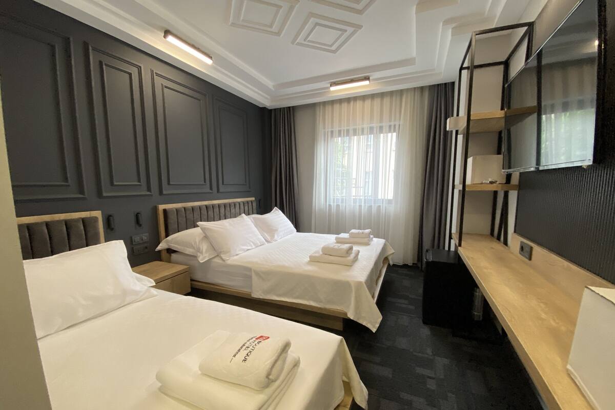 A hotel room with two beds, a TV, and a desk.