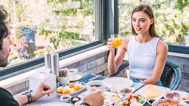 A dining table with various dishes, a glass of orange juice, and a view of greenery outside. - RW Boutique Hotel (Istanbul)