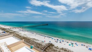 A beach with a pier extending into the ocean, white sand, and clear blue water. - Beach Colony East 15A- 3BD/3BA Gulf front w/Beach Service & Onsite Management (Navarre Beach)