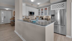 A modern kitchen with white cabinets, stainless steel appliances, and a central island. - Beach Colony East 15A- 3BD/3BA Gulf front w/Beach Service & Onsite Management (Navarre Beach)