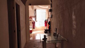 A narrow hallway with a glass table and chairs, leading to a room with a bed and a window. - LET'S ROLA (Campeche)