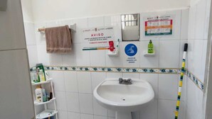 A bathroom with a sink, a towel rack, a broom, and a shelf with toiletries. - LET'S ROLA (Campeche)