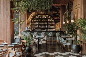 A bar area with a wooden ceiling, shelves of bottles, and tables with chairs. - Selvario 36 Hotel (Medellín)