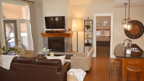 A cozy living room with a fireplace, a television, and a comfortable seating area. - Extraordinary Mountain Penthouse, Spectacular Views, Pool & Hot Tub, Park Pass (Canmore)