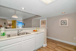 A modern kitchen with a built-in dishwasher, a sink, and a fruit bowl on the counter.