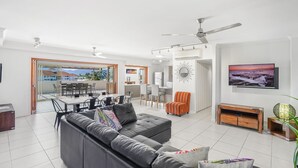 Een moderne woonkamer met een grijze bank, een eethoek, een keuken en een balkon met uitzicht.