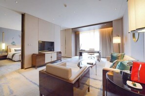 Een moderne hotelkamer met een bank, een televisie, een eettafel en een bed.