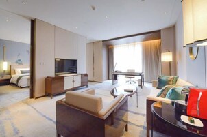 Una habitación de hotel moderna con sofá, televisor, mesa de comedor y cama.