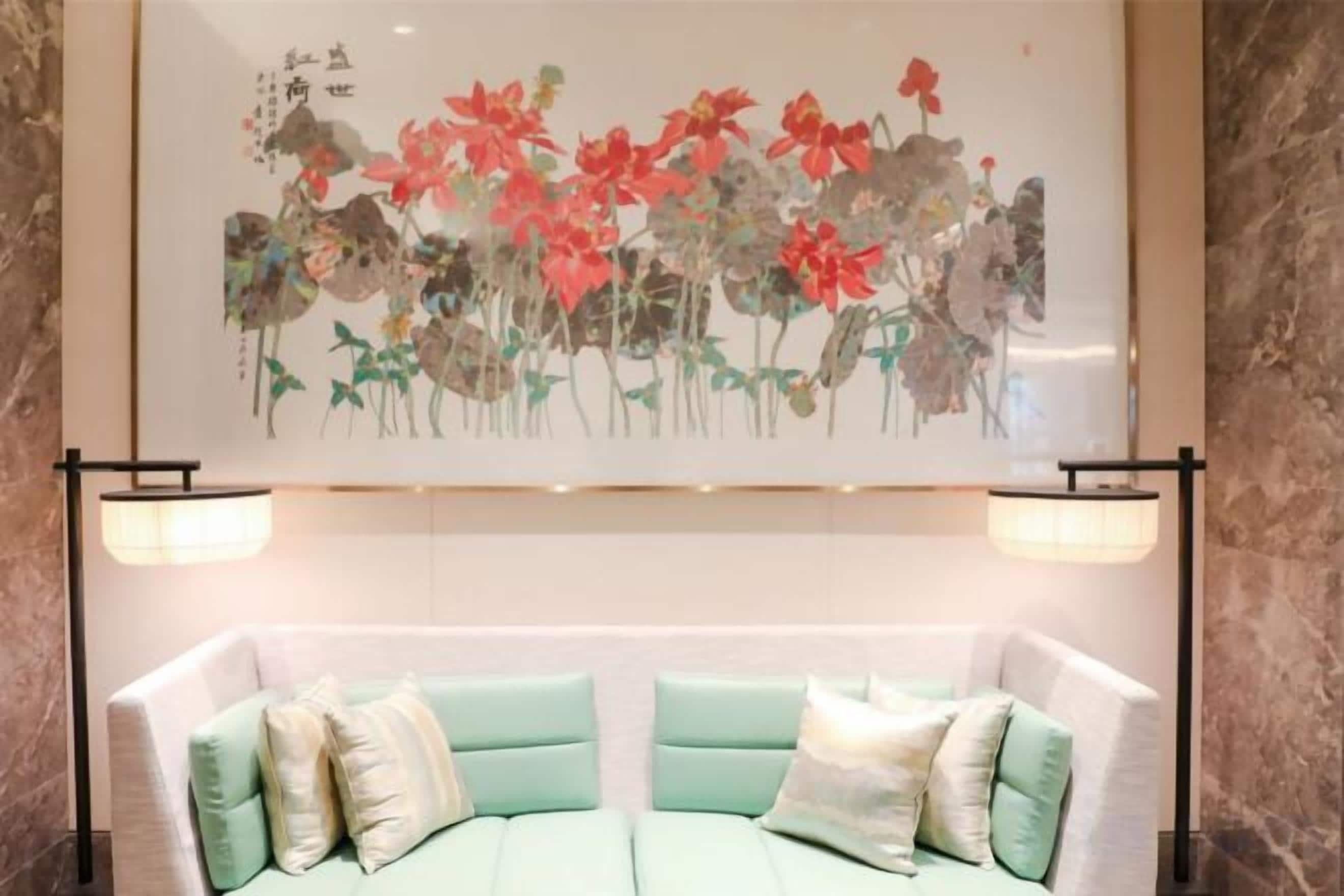 A room with a bed, a wall-mounted artwork, and two floor lamps.