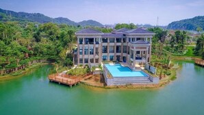A large, modern building with a swimming pool, surrounded by water and greenery. - Lotus Villa Hotel (Liuzhou)