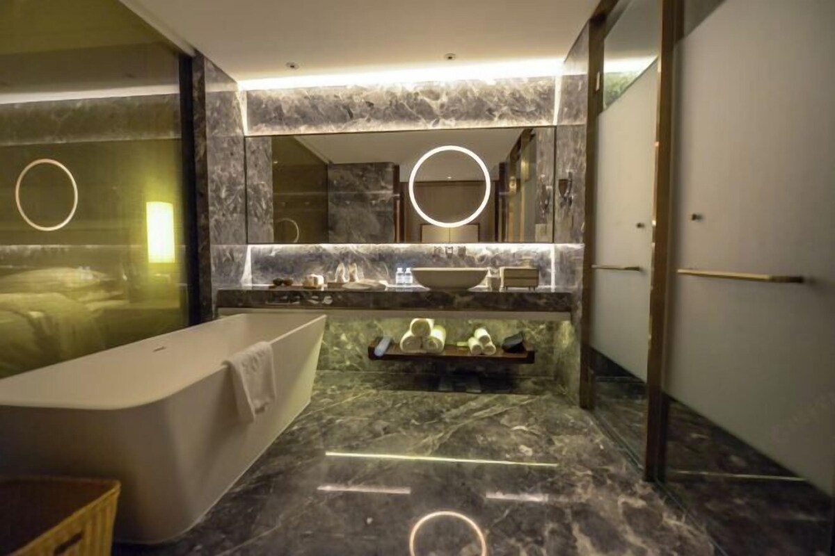 Een moderne badkamer met een vrijstaand bad, een wastafel met spiegel en een marmeren vloer.