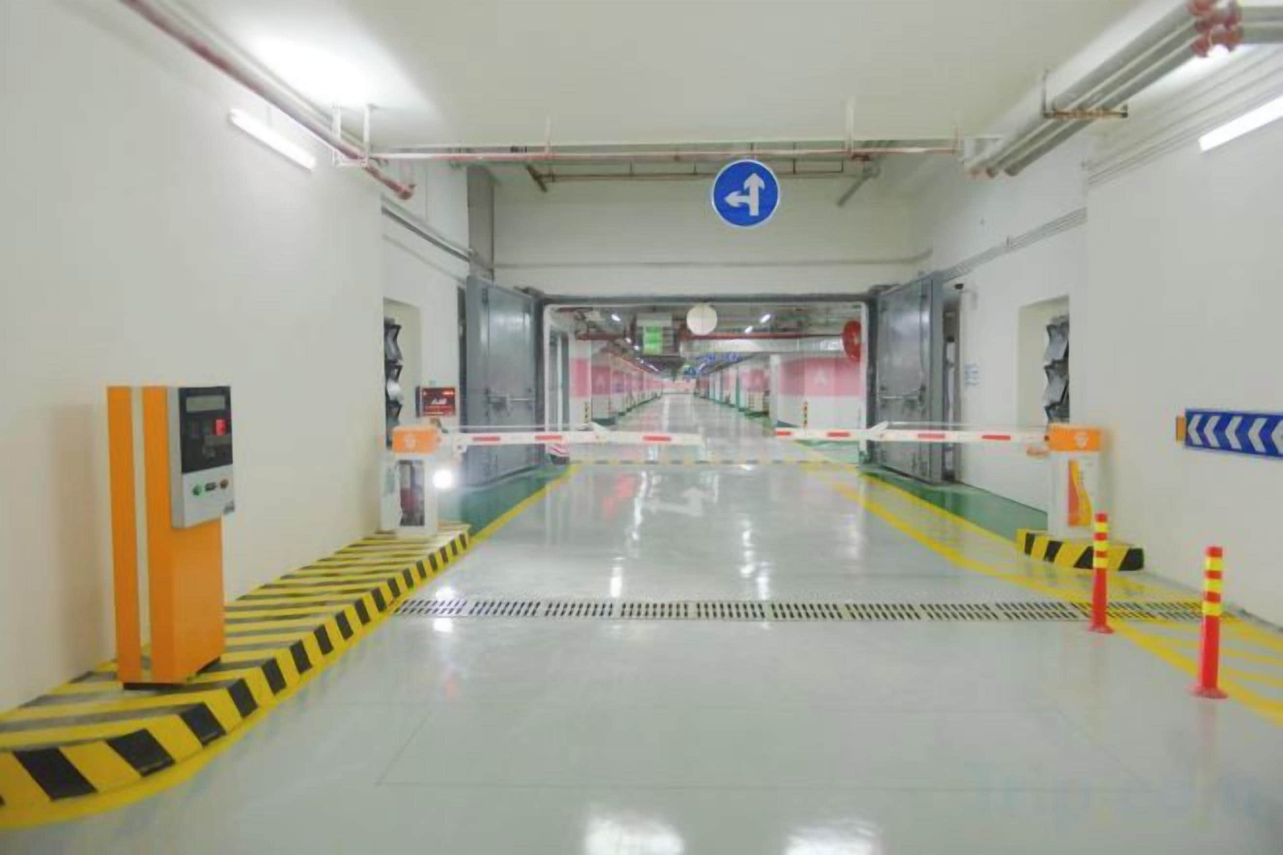 A corridor with a barrier gate, a control panel, and directional signage.