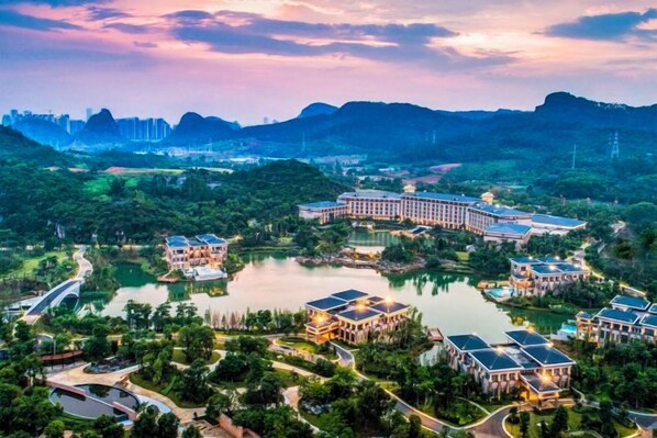 A resort with multiple buildings, a lake, and a mountainous backdrop. - Lotus Villa Hotel (Liuzhou)