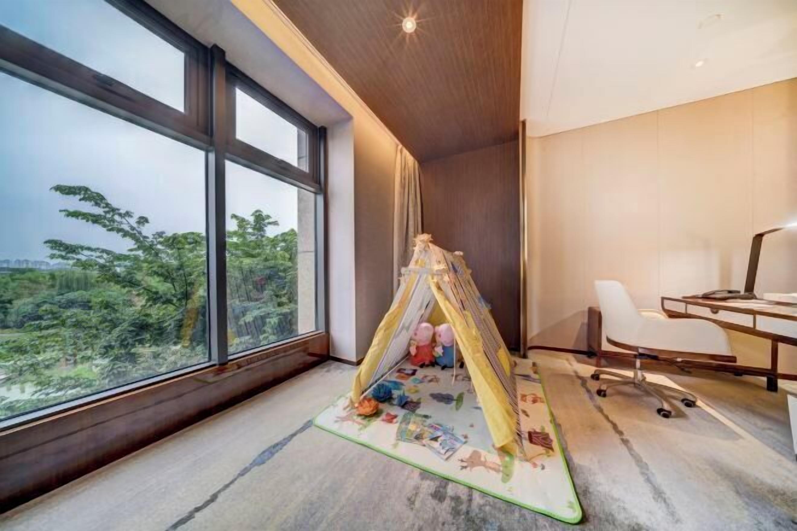 Una habitación moderna con ventanas amplias, un escritorio y una tienda de campaña para jugar.