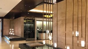 A modern hotel lobby with a central seating area, a reception desk, and a decorative wall with vertical light fixtures. - Lotus Villa Hotel (Liuzhou)
