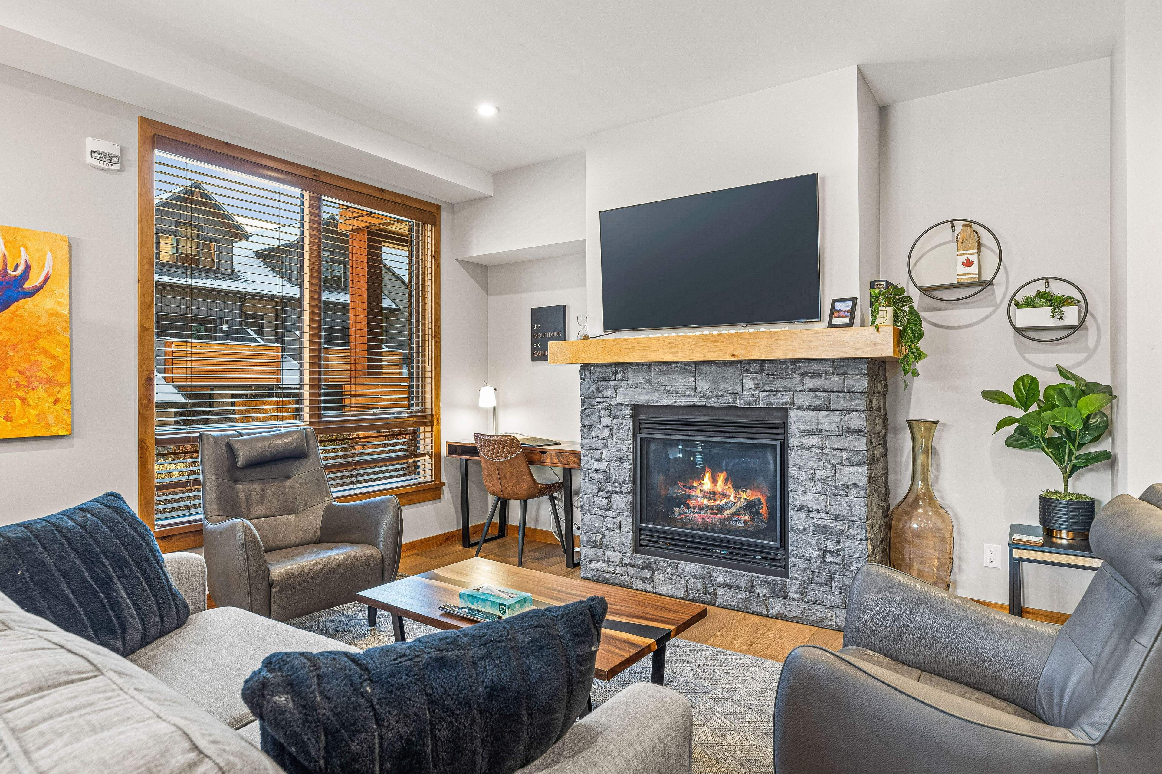Una sala de estar moderna con chimenea, asientos cómodos y un televisor grande.