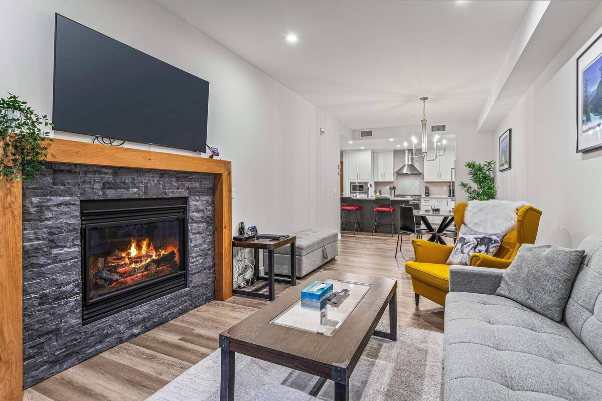 Una sala de estar moderna con chimenea, un sofá, una mesa de centro y un televisor montado en la pared.