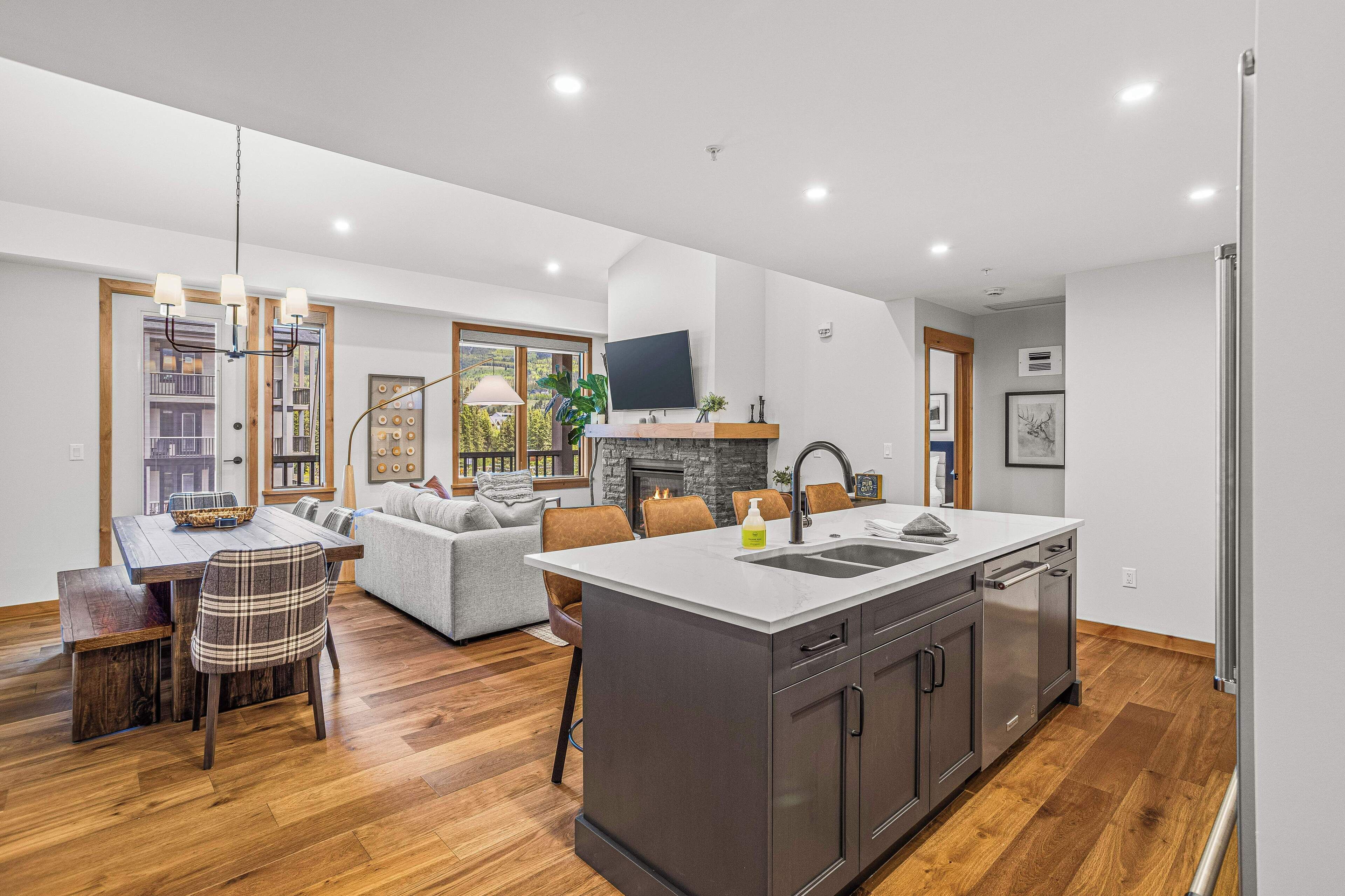 A modern kitchen with a large island, built-in appliances, and a dining area with a fireplace.