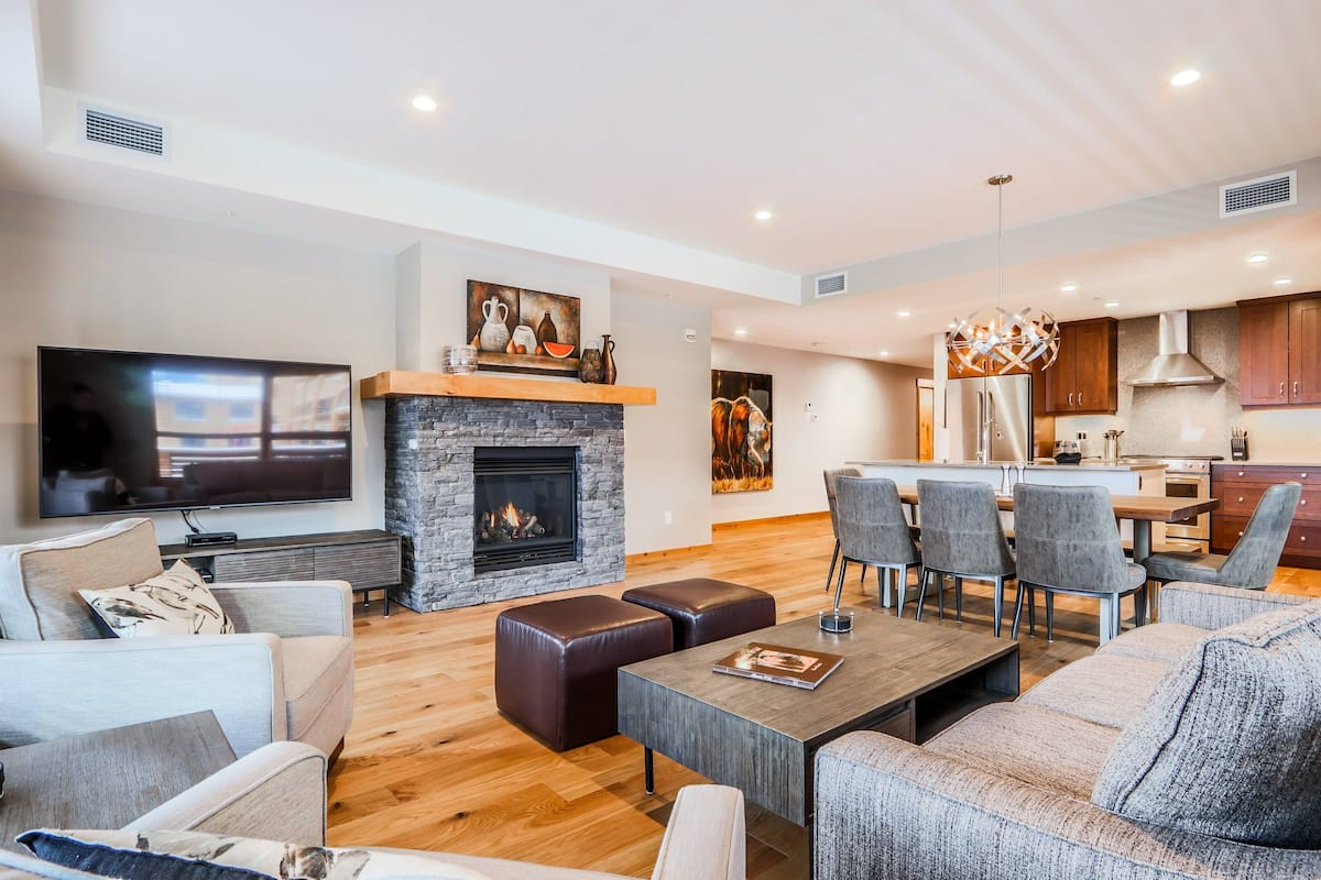 Una sala de estar moderna con chimenea, un televisor de pantalla plana y un comedor con sillas y una mesa.