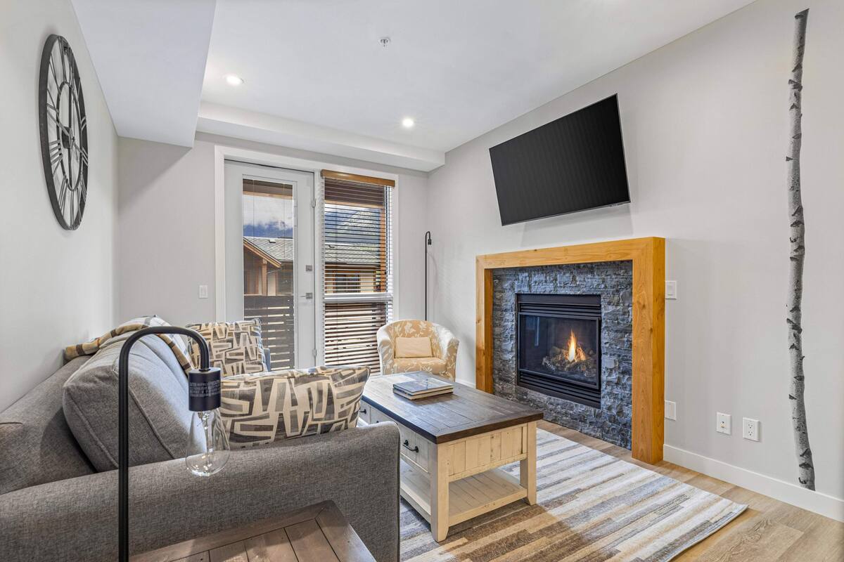 Una sala de estar moderna con chimenea, un sofá, una mesa de centro y un televisor montado en la pared.