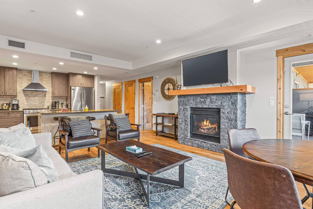 Una sala de estar moderna con chimenea, comedor y cocina.