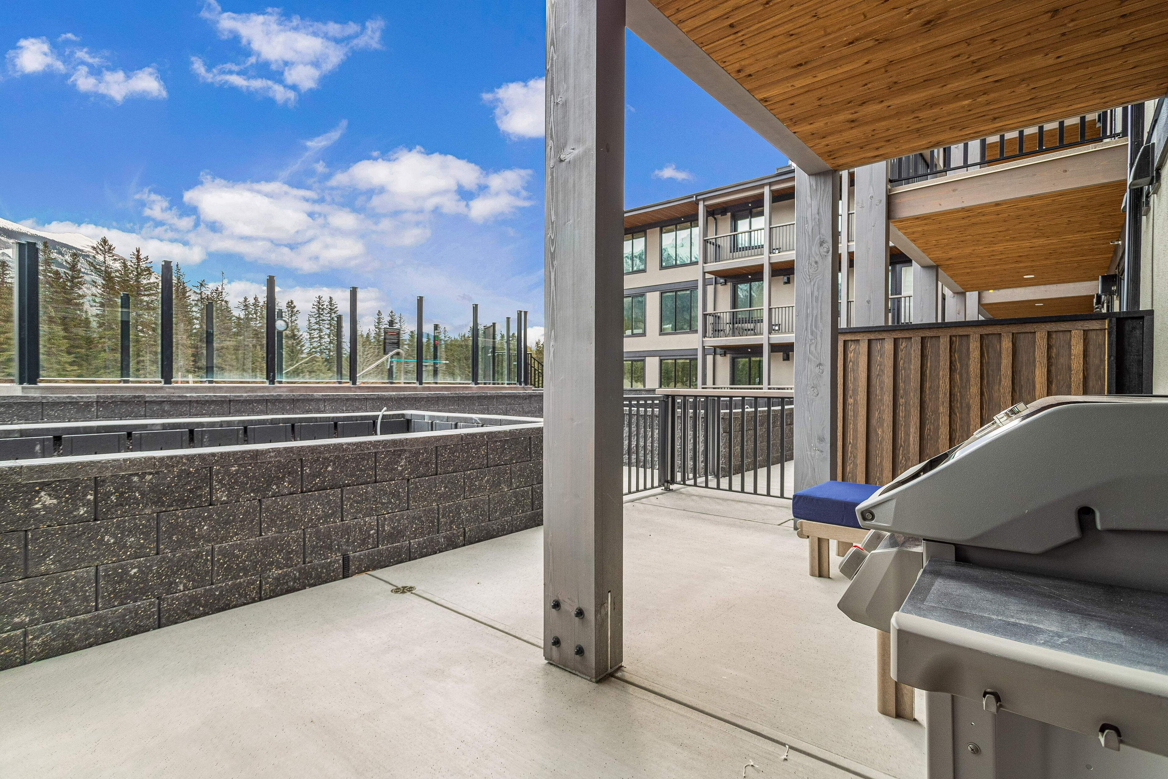 Un espacio al aire libre cubierto con una parrilla, vista a un edificio con varios balcones y una pared de piedra.