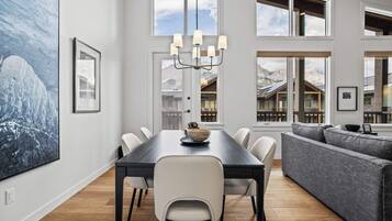Un espace de restauration moderne avec une longue table, des chaises blanches et un lustre.