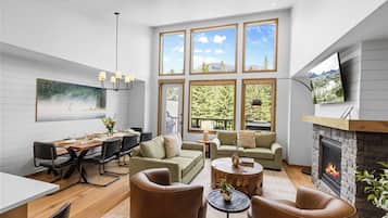 Una sala de estar moderna con chimenea, ventanas amplias, un comedor y una acogedora zona de estar.