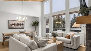 A modern living room with a sofa, coffee table, and a dining area with a table and chairs.