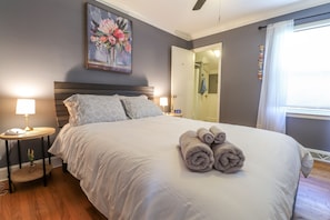Un lit bien fait, avec des serviettes pliées, une table de chevet avec une lampe et un tableau accroché au mur.