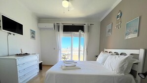Ein Hotelzimmer mit Bett, Schminktisch, Fernseher und Blick auf die Stadt durch das Fenster.