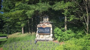 A sign for Crystal Mountain with a stone base and a wooden top, surrounded by lush greenery and a field of red flowers. - Beautiful Cabin located on the Betsie River and close to Crystal Mountain Resort (Thompsonville)