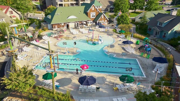 A swimming pool with multiple lanes, surrounded by lounge chairs and umbrellas. - Beautiful Cabin located on the Betsie River and close to Crystal Mountain Resort (Thompsonville)