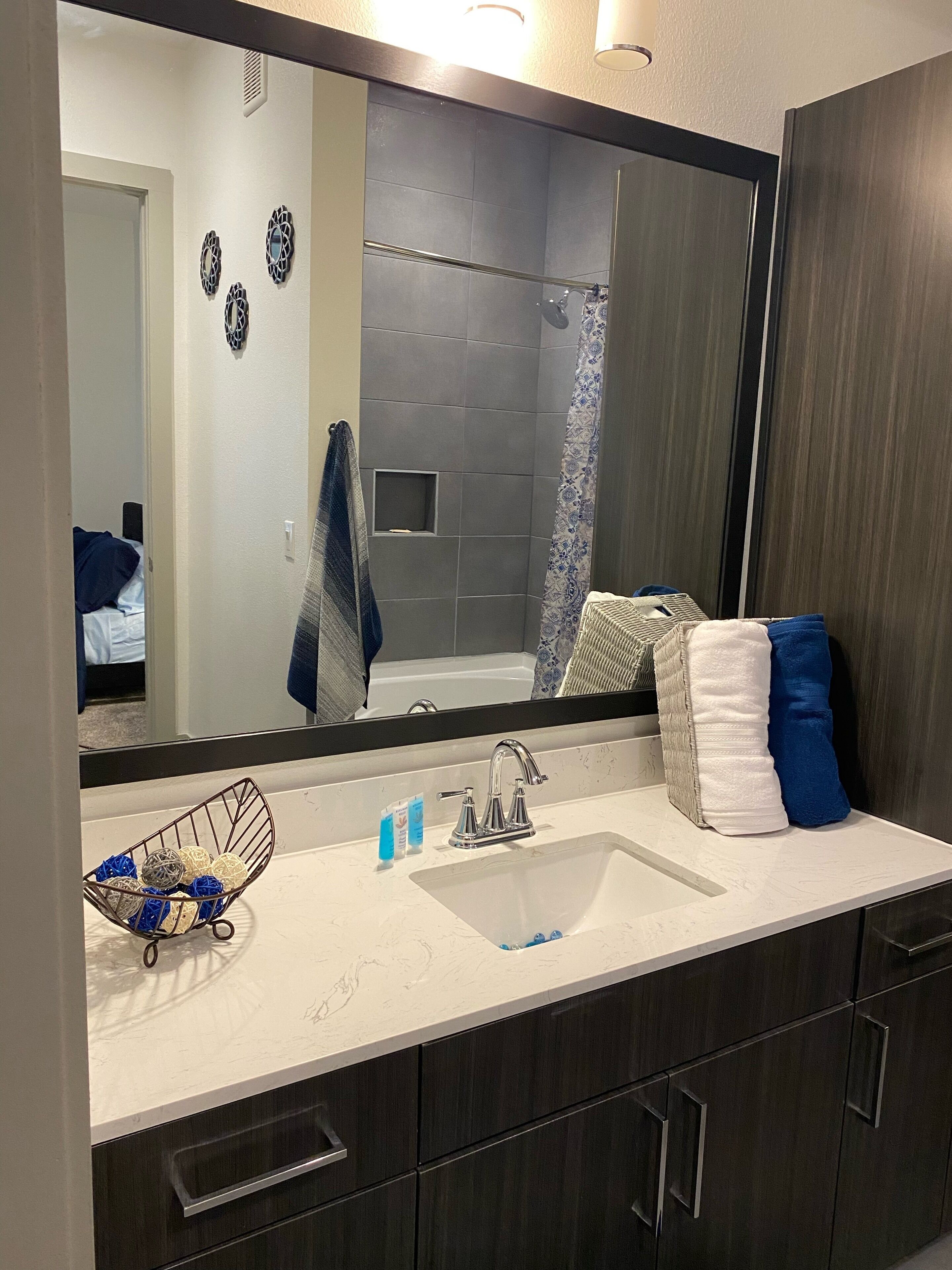 A bathroom with a large mirror, a sink, and a shower area.