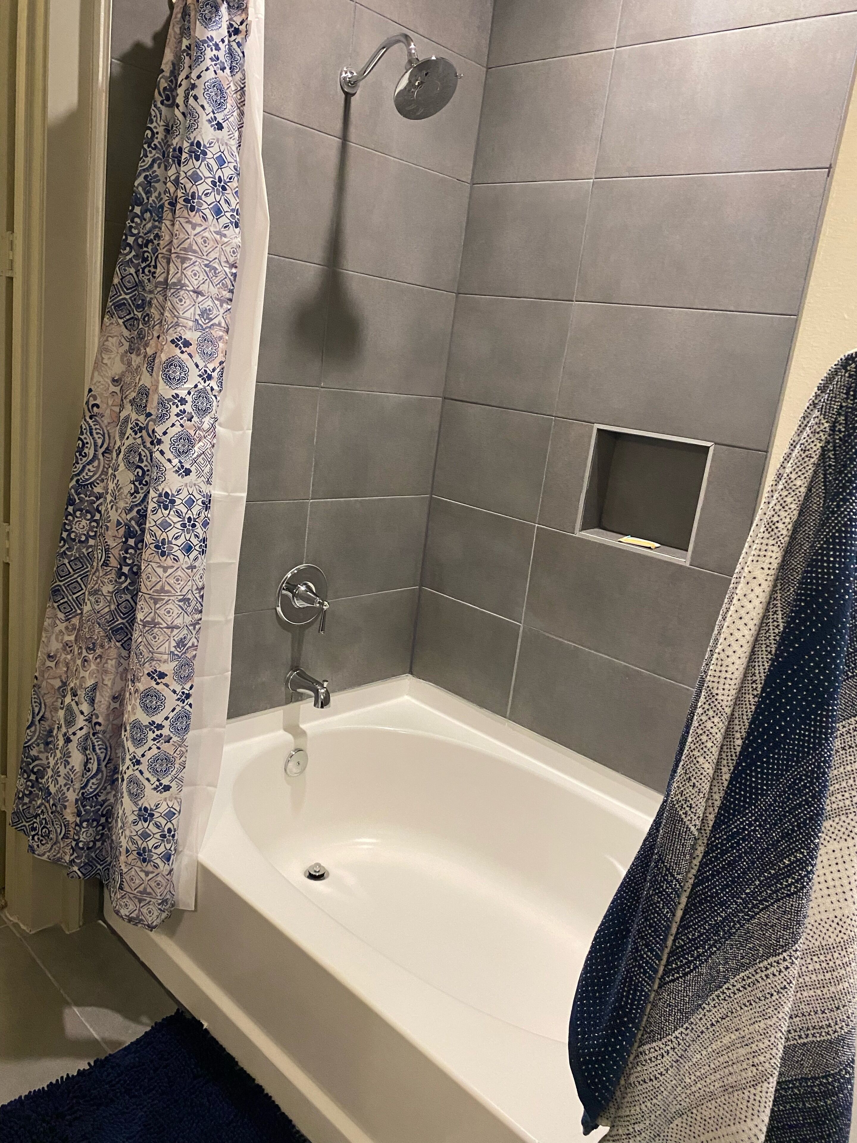 Een badkamer met een bad, een douchekop en een handdoekhouder.