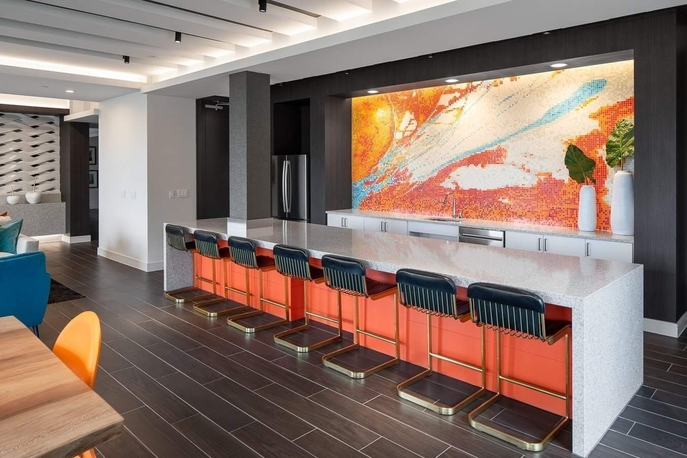 Una cocina moderna con barra, suelo de madera oscura y un llamativo salpicadero de mosaico.